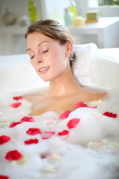 Belle femme relaxante dans un bain aux pétales de rose — Photo