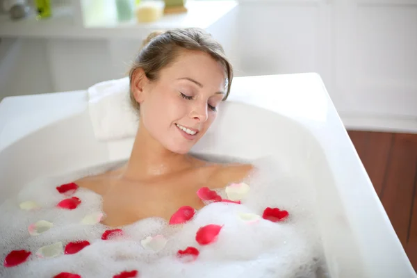 Bella donna rilassante in bagno con petali di rosa — Foto Stock