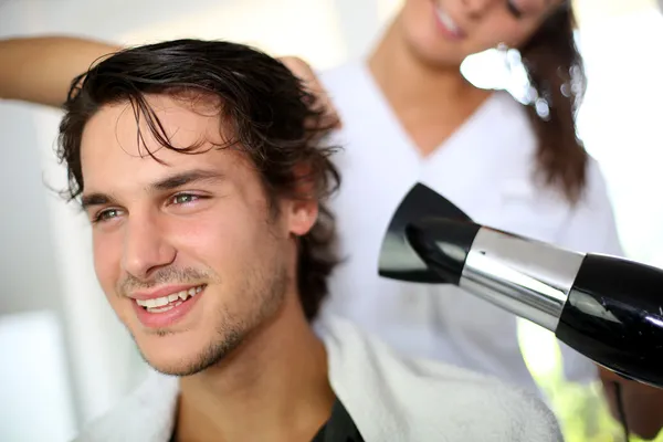 Junger Mann im Schönheitssalon lässt sich die Haare trocknen — Stockfoto