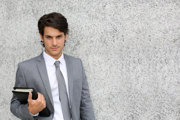 Nahaufnahme eines jungen Geschäftsmannes, der sich an die Wand lehnt — Stockfoto