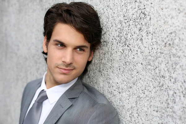 Closeup of handsome businessman leaning on wall — Stock Photo, Image