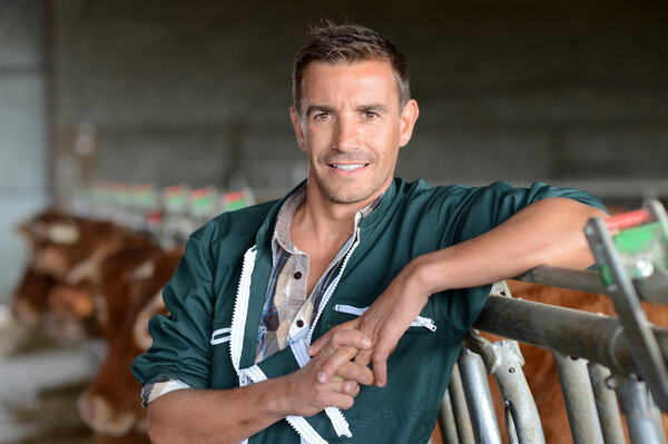 Portrait of smiling herdsman standing in barn