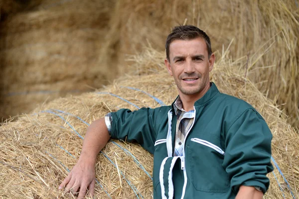 Portret van lachende landbouwer permanent door hooibergen — Stockfoto