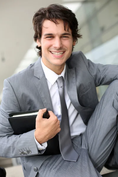 Smiling young businessman sitting outside building Royalty Free Stock Images