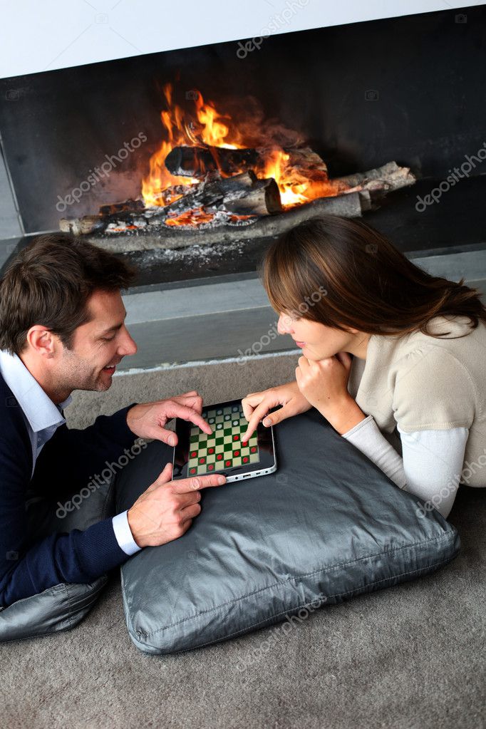 Fotos de Pareja sentada junto a la chimenea y websurf con tablet