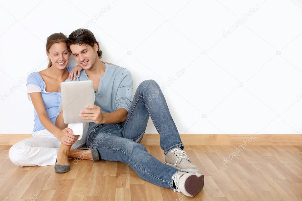 Couple using tablet laying on the floor at home