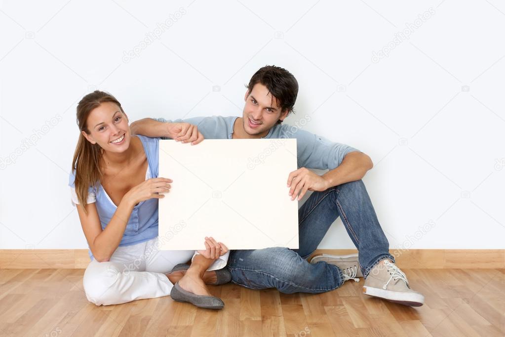 Couple sitting on the floor with message board