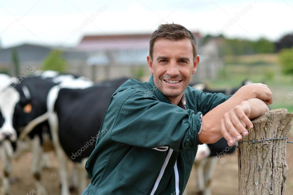 Herdsman standing in front of cattle in farm — Stock Photo © Goodluz