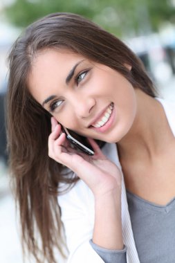 Şehirdeki telefonda konuşurken gülümseyen güzel kız