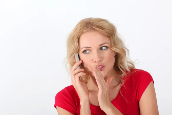 Porträt einer blonden Frau mit rotem Hemd, die am Telefon Geheimnis verrät — Stockfoto