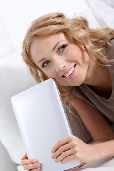 Mujer rubia sonriente en casa usando tableta electrónica —  Fotos de Stock