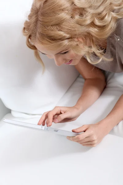 Leende blond kvinna hemma med hjälp av elektroniska tablett — Stockfoto