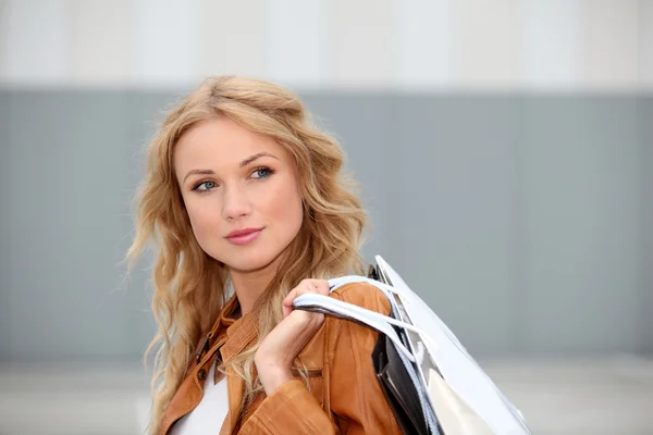 Mooie vrouw in stad houden shopping tassen — Stockfoto