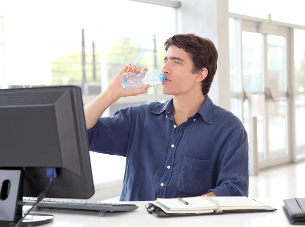 Office worker drinking water in front of desktop computer