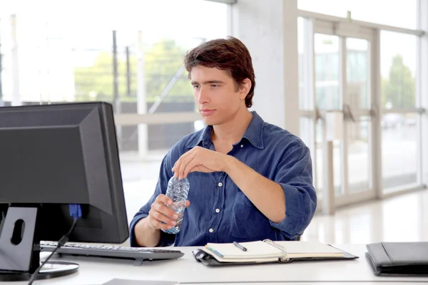 Ofis işçi içme suyu masaüstü bilgisayar önünde — Stok fotoğraf