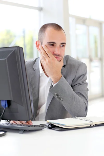 Uomo d'affari davanti al computer desktop con sguardo premuroso — Foto Stock