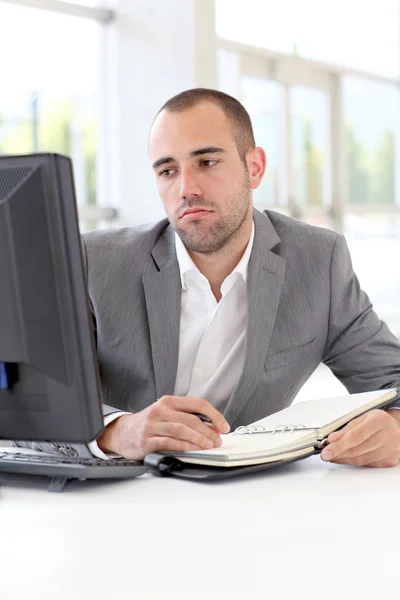 Geschäftsmann schreibt mit gelangweiltem Blick auf Tagesordnung — Stockfoto