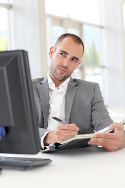 Zakenman in kantoor schrijven op agenda — Stockfoto