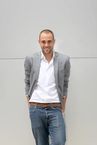 Guapo hombre sonriente apoyado en la pared —  Fotos de Stock