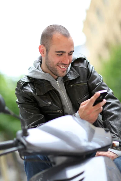 Ung man sitter i motorcykeln med telefon — Stockfoto