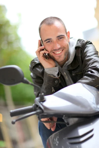 Young man sitting in motorcycle with telephone — Stock Photo, Image