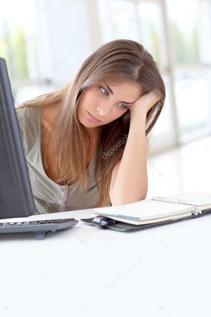 Exhausted young woman sitting in front of computer