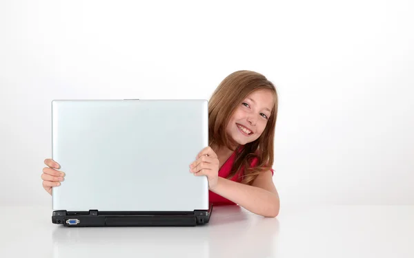 Portrait of blond little girl behind laptop computer — Stock Photo, Image