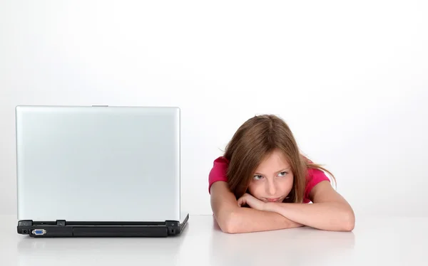 Girl with thoughtful look next to laptop computer — Stock Photo, Image