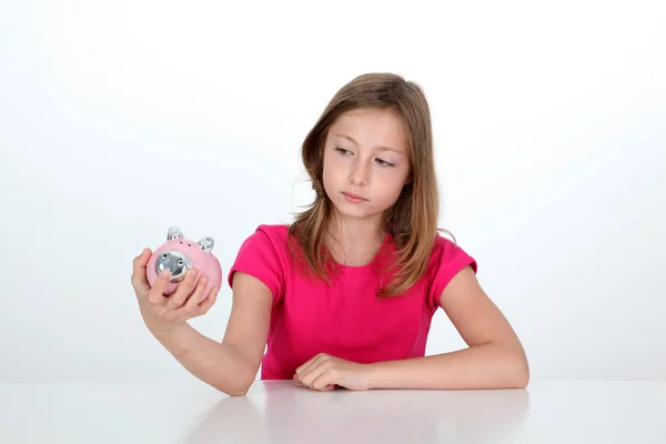 Portret van een jong meisje op zoek bij piggy bank — Stockfoto