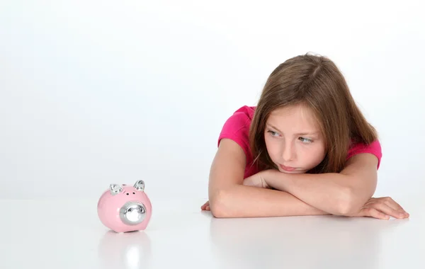 看着猪存钱罐的年轻女孩的肖像 — 图库照片