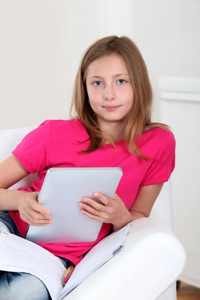 Menina da escola usando tablet eletrônico no sofá — Fotografia de Stock
