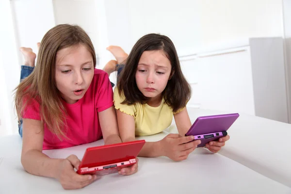 Les jeunes filles jouent avec la console de jeu sur le canapé — Photo