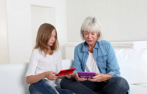 Seniorin und Mädchen spielen mit Spielkonsole — Stockfoto