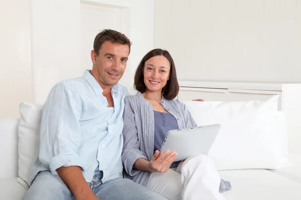 Couple dans le canapé en utilisant une tablette électronique — Photo