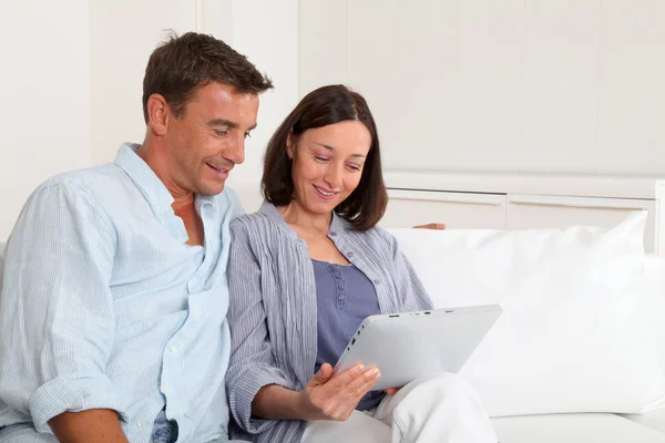 Casal no sofá usando tablet eletrônico — Fotografia de Stock