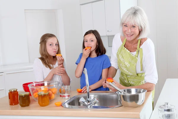 Senior woman making apricot jam with grandkids — Stock Photo, Image
