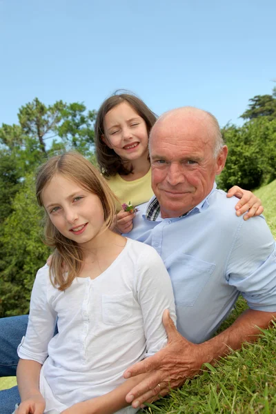 Grootvader met kleinkinderen, zitten in park — Stockfoto