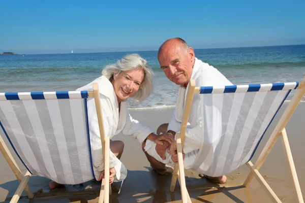 Retrato de casal sênior sentado em cadeiras de praia — Fotografia de Stock