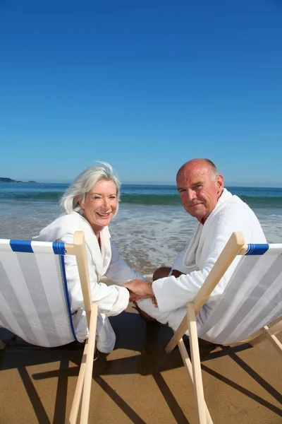 Retrato de casal sênior sentado em cadeiras de praia — Fotografia de Stock