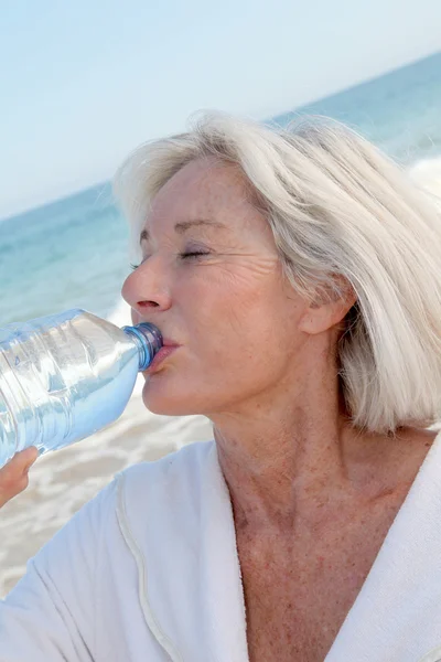 Donna anziana che beve acqua dalla bottiglia — Foto Stock