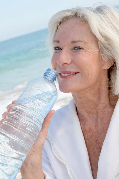 Старша жінка п'є воду з пляшки — стокове фото