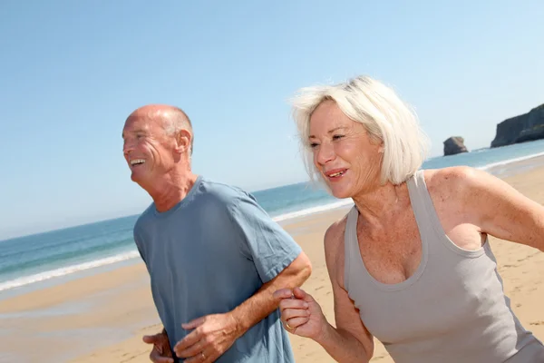 Äldre par jogging på en sandstrand — Φωτογραφία Αρχείου