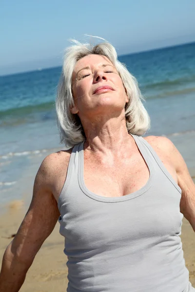 Ανώτερος γυναίκα χαλαρώνοντας στην παραλία — Φωτογραφία Αρχείου