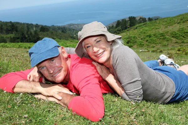 Seniorenpaar ruht sich an sonnigem Tag auf Wiese aus — Stockfoto