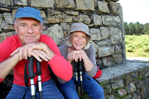 Portret van gelukkig senior wandelaars rusten door stenen huis — Stockfoto