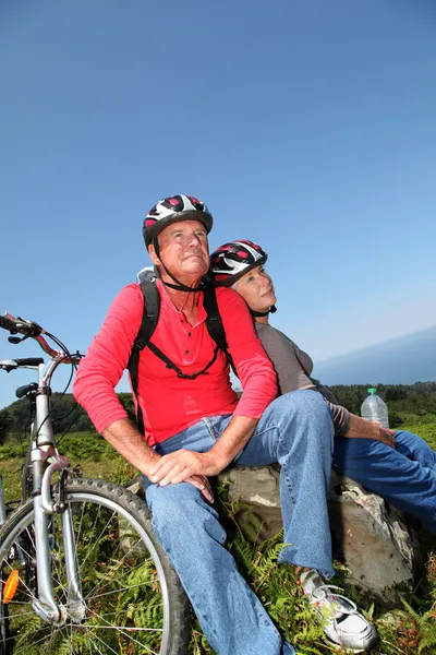 Senior couple riding mountain bikes in natural landscape — Stock Photo, Image