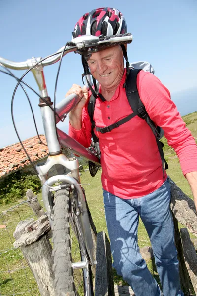 Hombre mayor llevando bicicleta de montaña — Foto de Stock