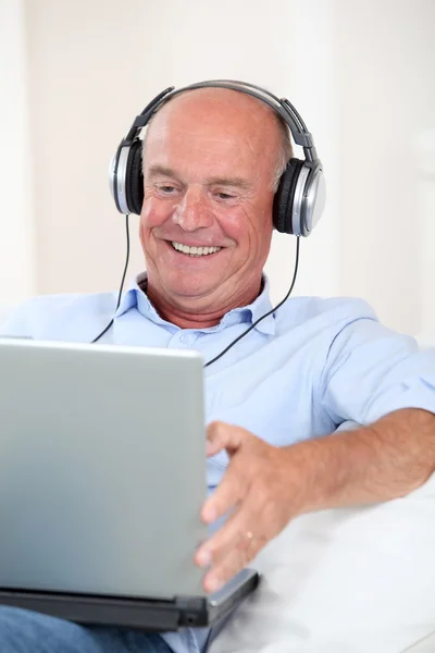 Äldre man lyssnar på musik med hörlurar — Stockfoto