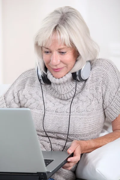 Mulher sênior ouvindo música com fones de ouvido — Fotografia de Stock