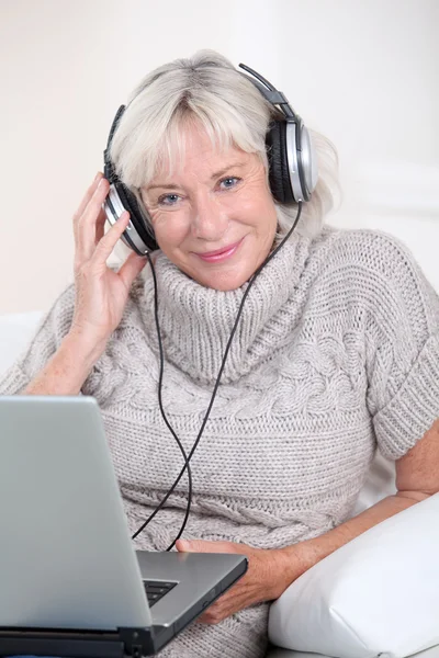 Mujer mayor escuchando música con auriculares — Foto de Stock